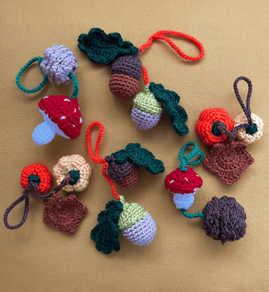Autumnal crochet keychains featuring acorn and oak leaf, mushroom and pine cone, and pumpkin and maple leaf designs