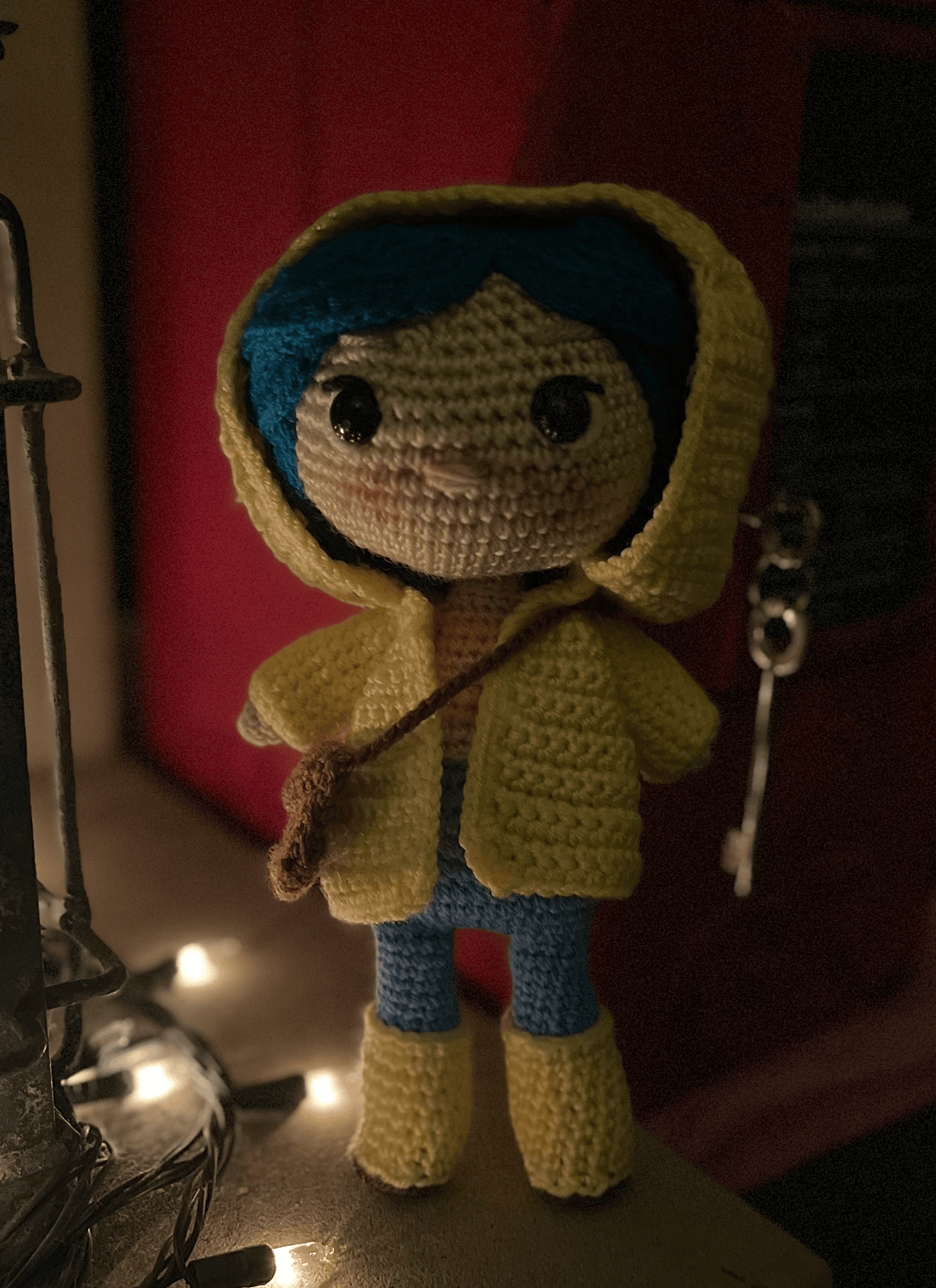 Coraline inspired crochet doll with blue hair and yellow raincoat, handmade display collectible