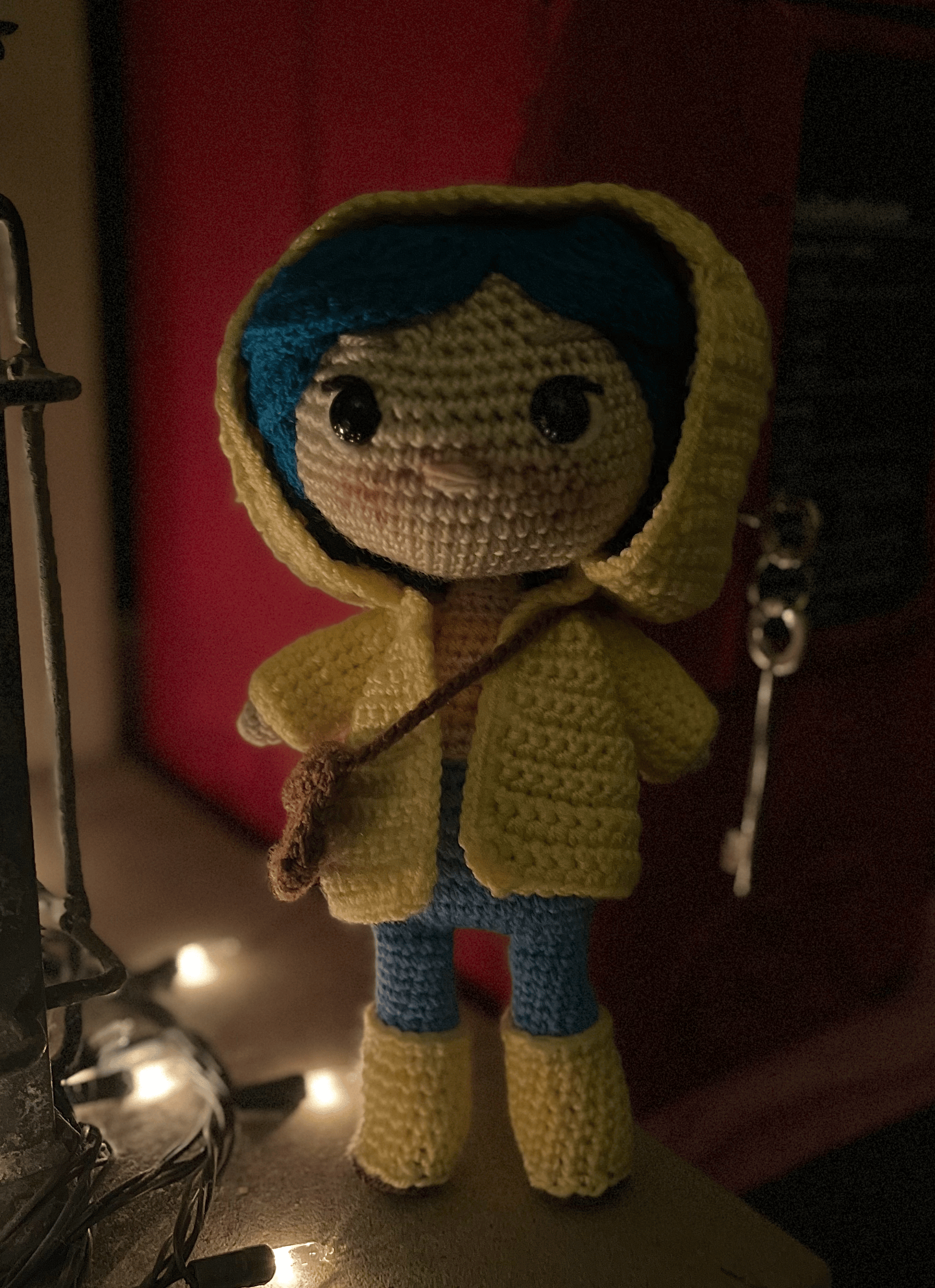 Coraline inspired crochet doll with blue hair and yellow raincoat, handmade display collectible
