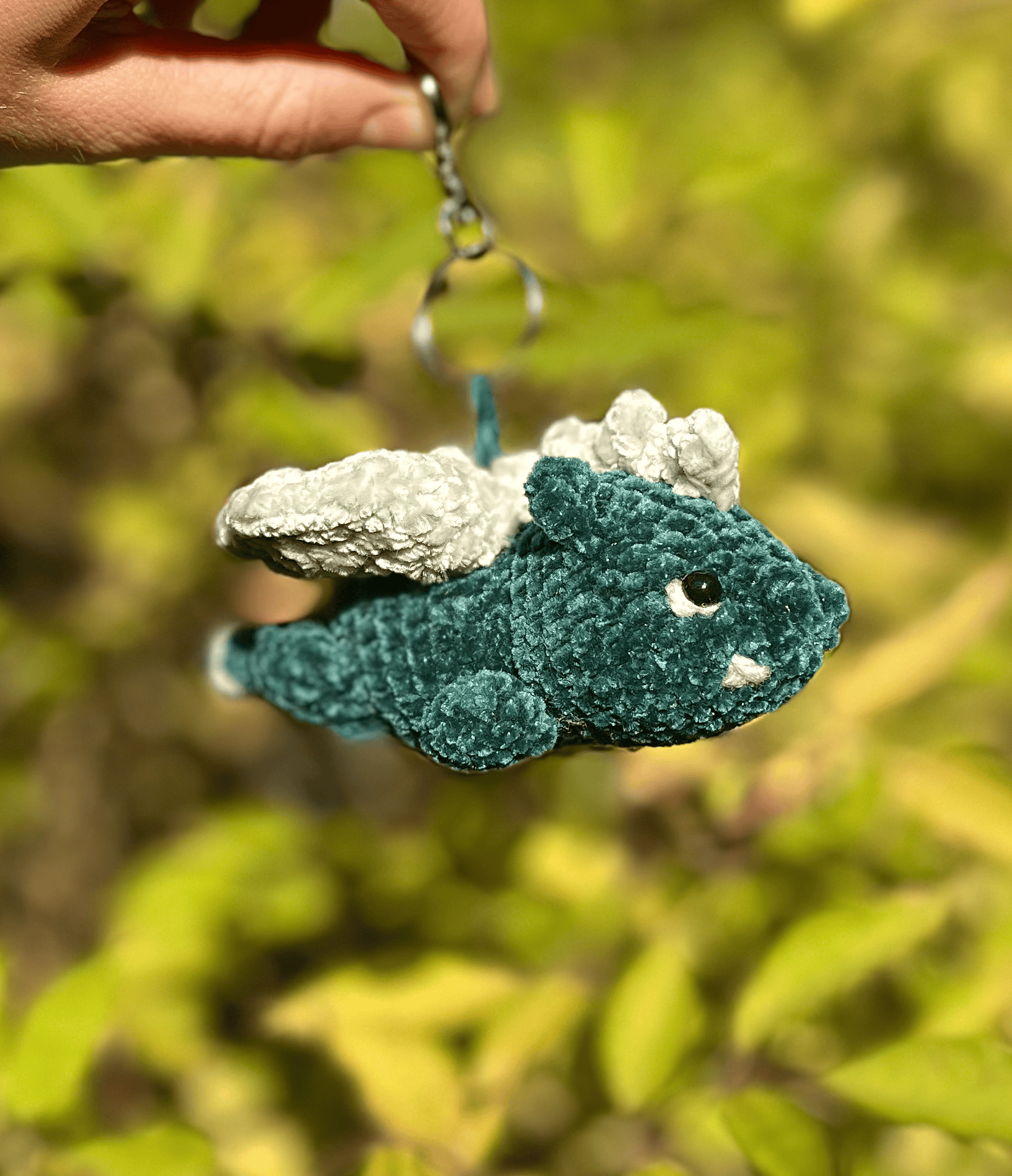 Handmade plush crochet dragon keyring attached to a bag, cute fantasy accessory and mythical creature charm
