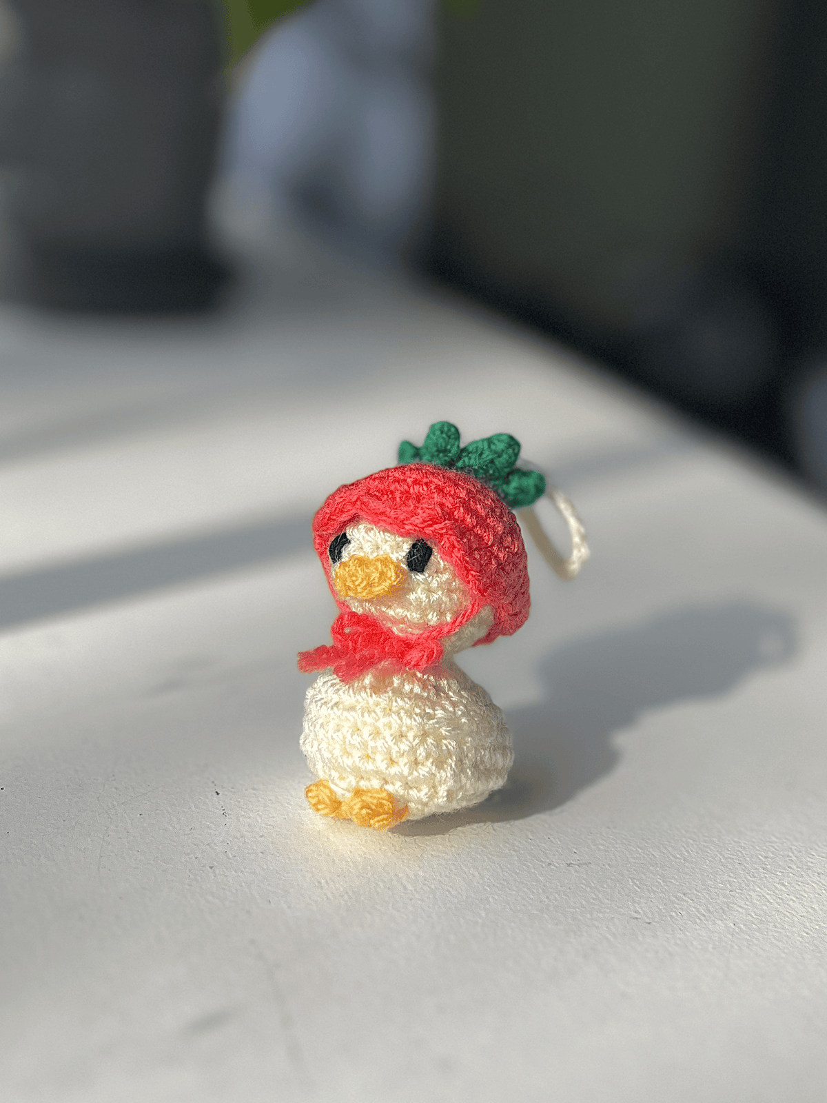 Small crochet duckling keychain wearing a flower hat, cute Easter accessory and spring crochet bag charm