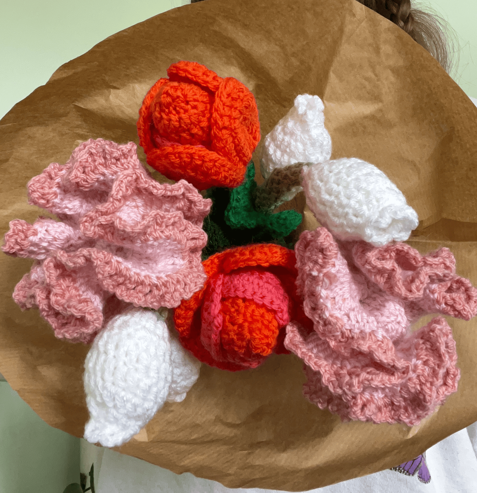 Close-up of handmade crochet tulips, carnations and lily of the valley flowers in a spring floral arrangement
